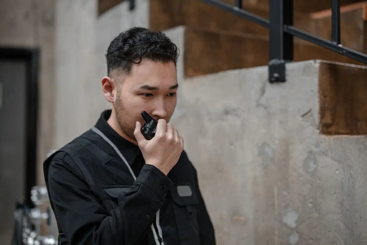 A security officer in black speaking into a radio