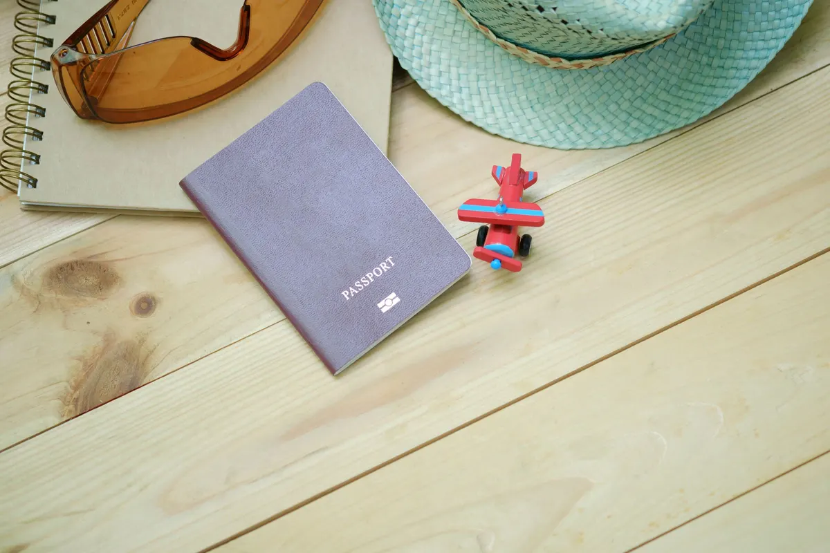 A passport beside a sun hat and sunglasses