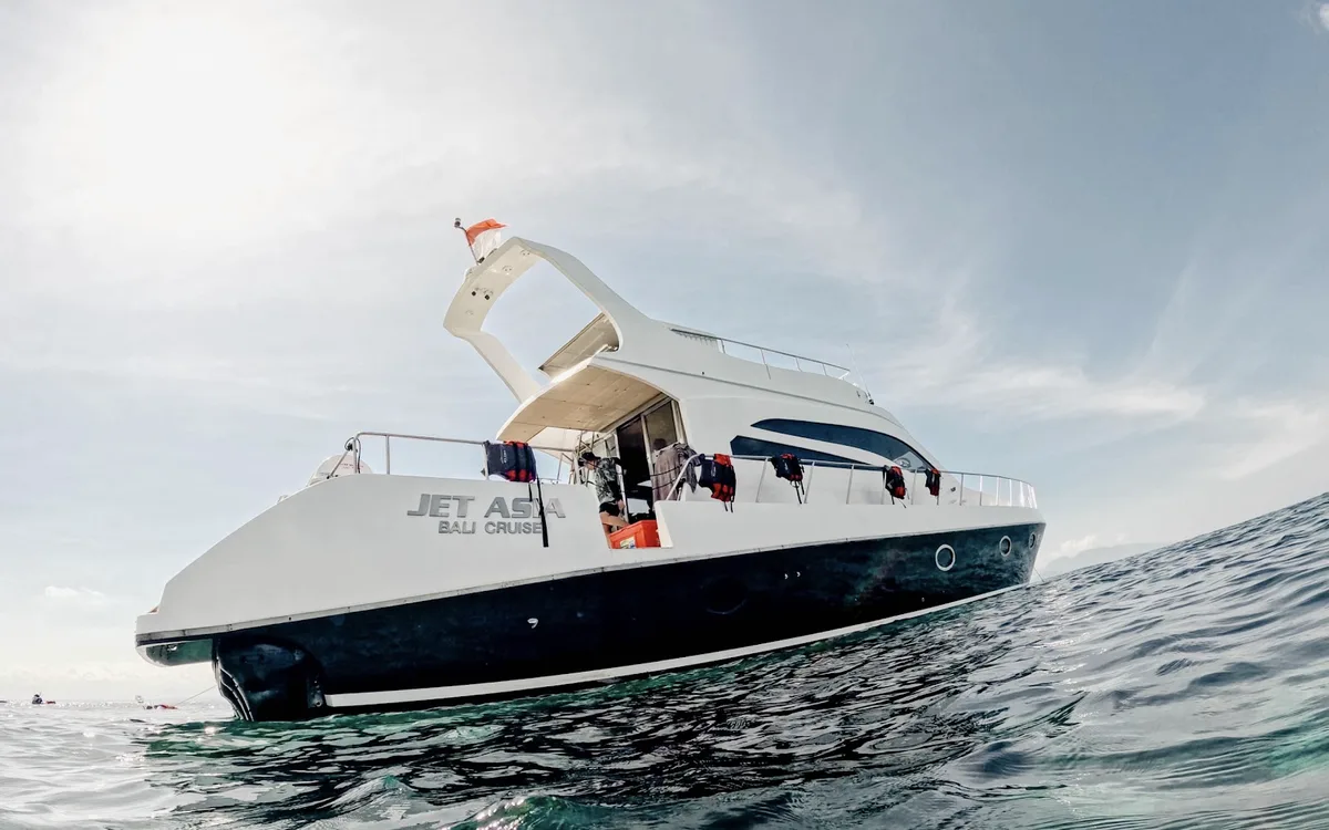 A white and navy 20-metre motor yacht at anchor, seen from the water