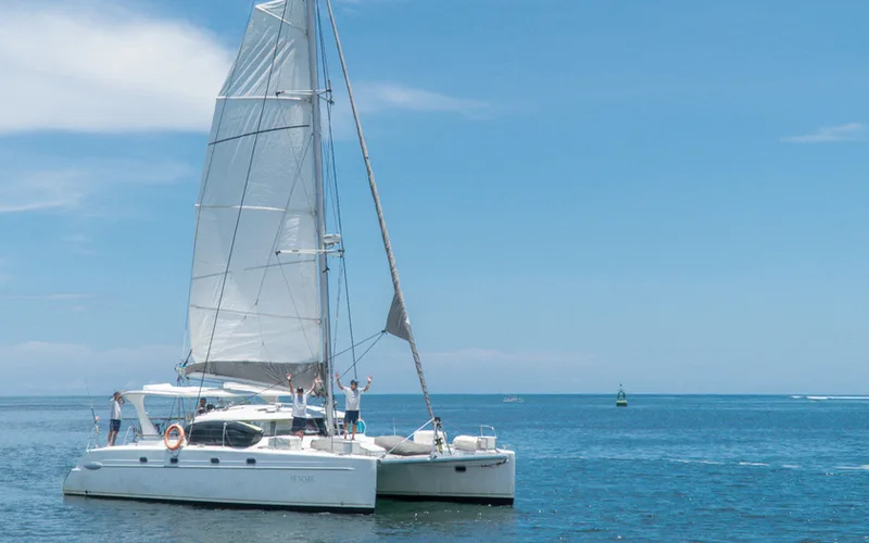 A white sailing catamaran under sail on calm blue sea